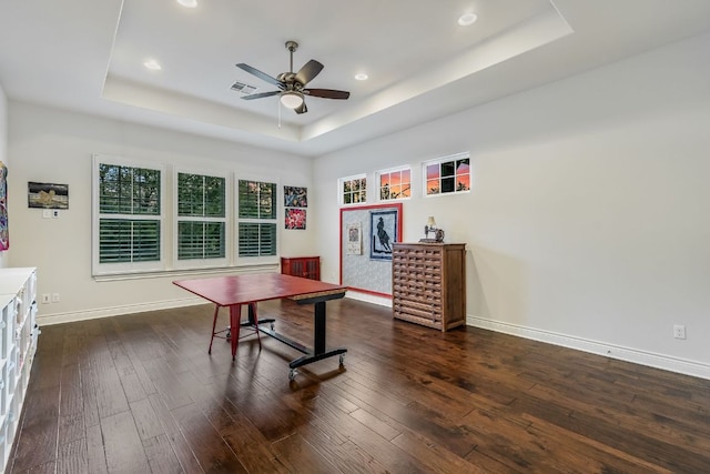 office area featuring baseboards, a ceiling fan, a tray ceiling, and dark wood finished floors