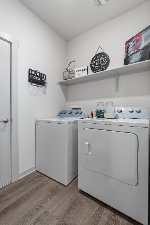 laundry area featuring separate washer and dryer, wood finished floors, and laundry area