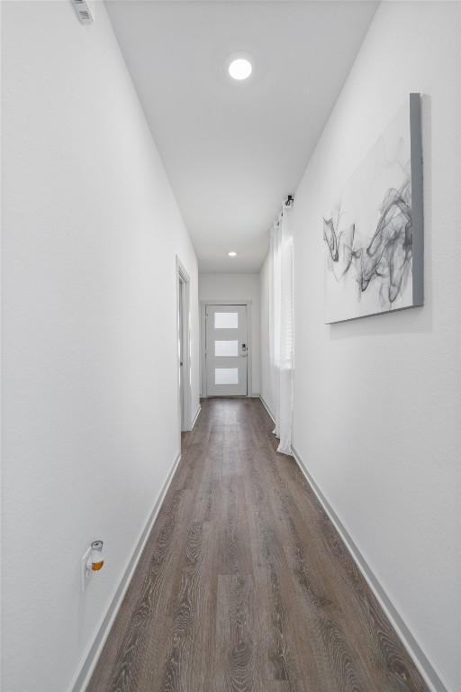 corridor with baseboards and wood finished floors