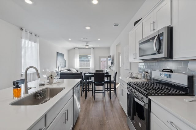 kitchen featuring wood finished floors, a sink, open floor plan, appliances with stainless steel finishes, and visible vents