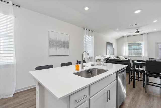 kitchen with light wood-style flooring, visible vents, stainless steel dishwasher, and a sink