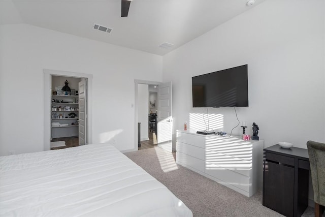 carpeted bedroom featuring a spacious closet, vaulted ceiling, visible vents, and a ceiling fan