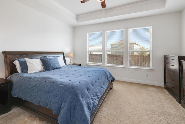 bedroom with a raised ceiling, a ceiling fan, ornamental molding, baseboards, and light colored carpet
