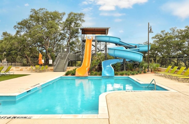community pool with a water slide, stairs, and a patio