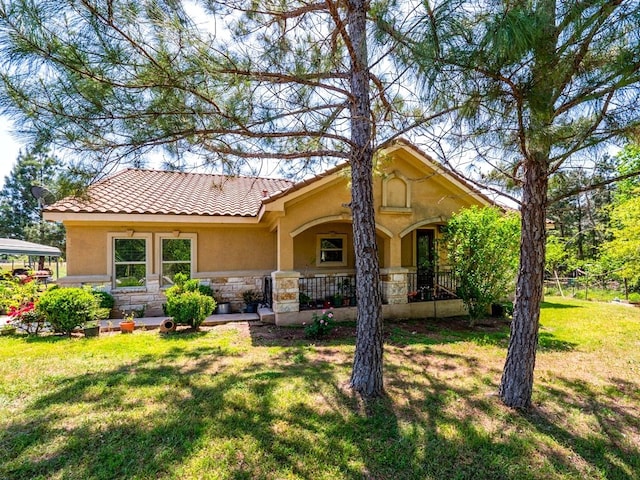 316 County Rd, Bastrop, TX 78602 - view of front of house with stucco siding, stone siding, a front yard, a tile roof, and a porch