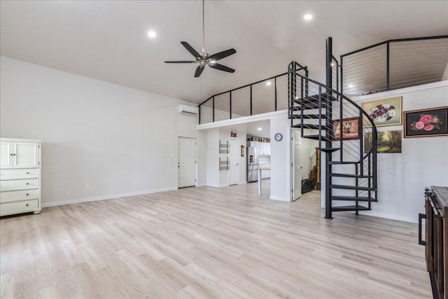 unfurnished living room featuring stairway, a ceiling fan, high vaulted ceiling, and light wood-style flooring