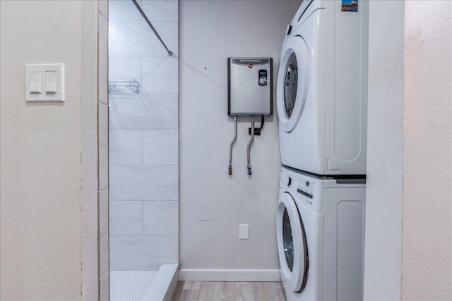 washroom featuring light wood-style floors, baseboards, stacked washer / dryer, and laundry area