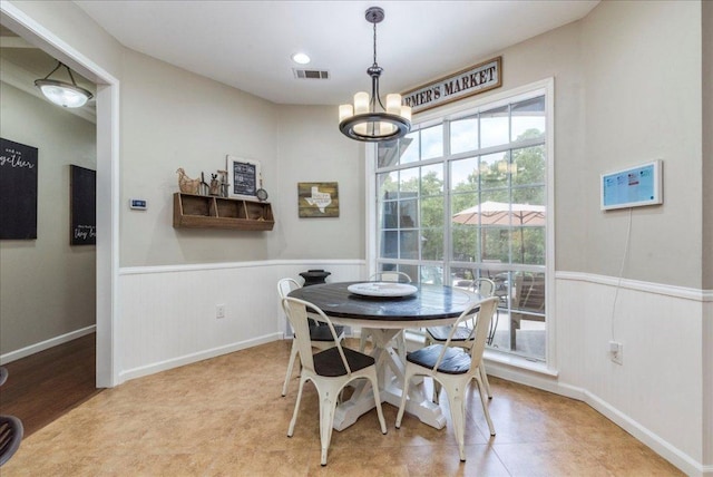 dining room featuring visible vents, a notable chandelier, and wainscoting