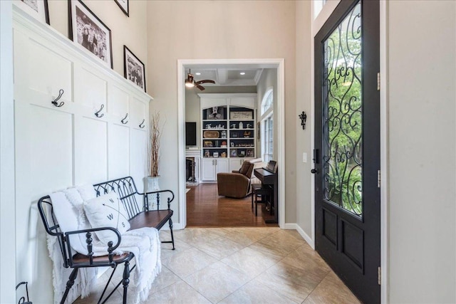 mudroom featuring ceiling fan, a high ceiling, light tile patterned floors, and baseboards