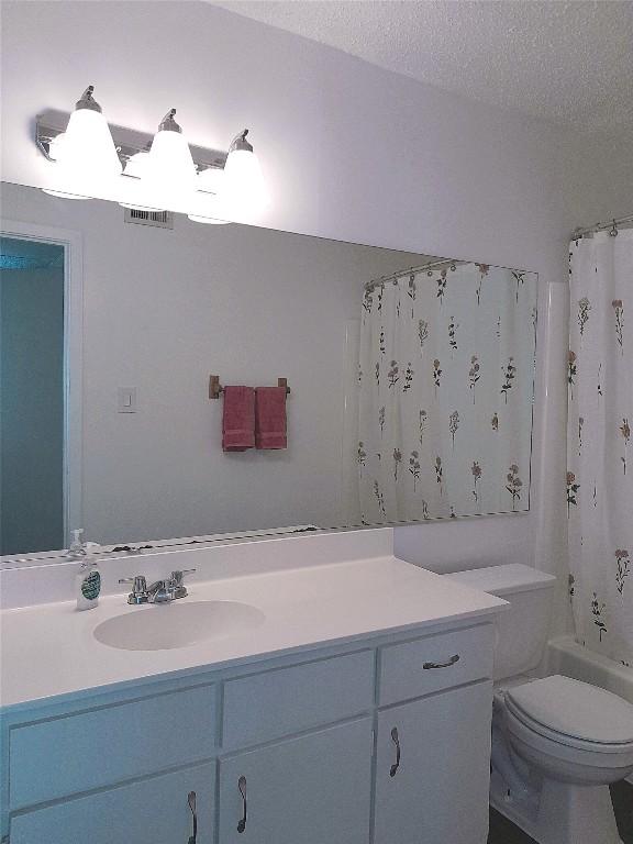 910 Duncan Ln Unit 27, Austin, TX 78705 - bathroom featuring vanity, shower / tub combo with curtain, and a textured ceiling