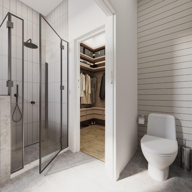 bathroom with a walk in closet, a shower stall, and toilet