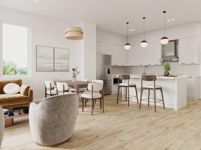 interior space with a kitchen breakfast bar, modern cabinets, stainless steel fridge with ice dispenser, white cabinets, and wall chimney exhaust hood
