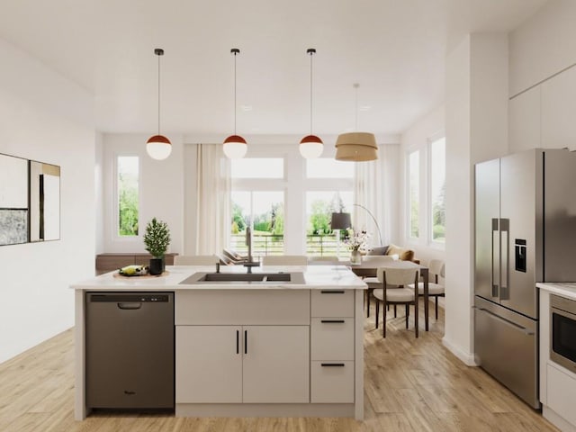 kitchen featuring light countertops, a healthy amount of sunlight, appliances with stainless steel finishes, and a center island with sink