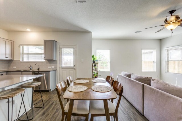 dining room featuring dark wood-style flooring, a ceiling fan, a textured ceiling, and visible vents