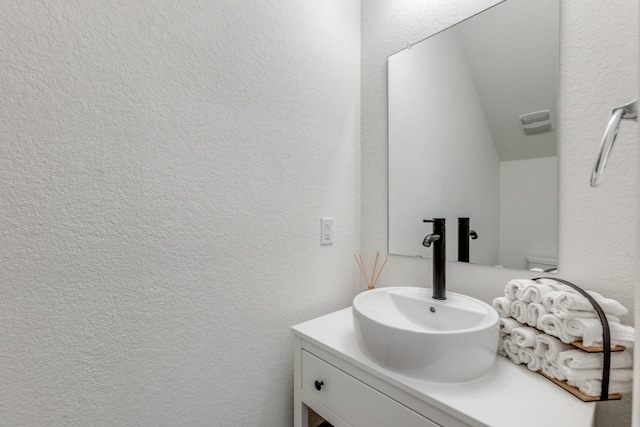 bathroom featuring a textured wall and vanity