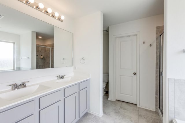 bathroom with double vanity, a shower stall, toilet, and a sink