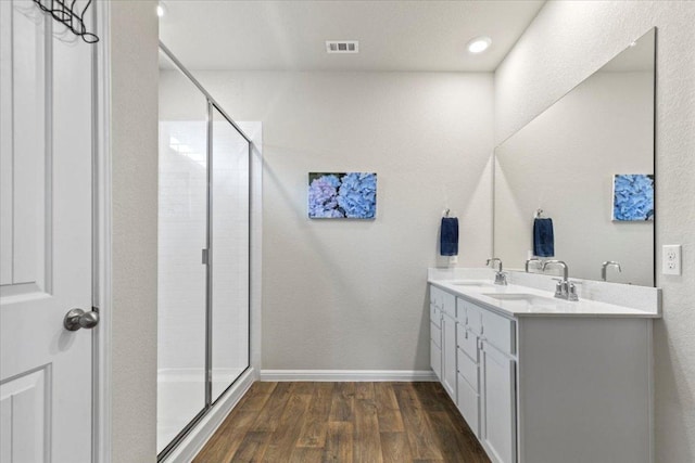 609 Bluffview Dr, Bastrop, TX 78602 - bathroom with wood finished floors, a shower stall, double vanity, and baseboards