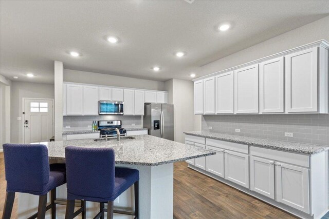 609 Bluffview Dr, Bastrop, TX 78602 - kitchen with appliances with stainless steel finishes, backsplash, a sink, recessed lighting, and a kitchen island with sink
