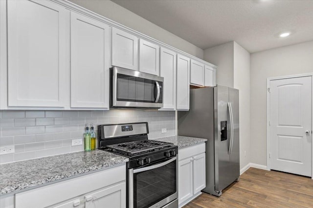 609 Bluffview Dr, Bastrop, TX 78602 - kitchen with appliances with stainless steel finishes, dark wood-type flooring, baseboards, white cabinetry, and backsplash