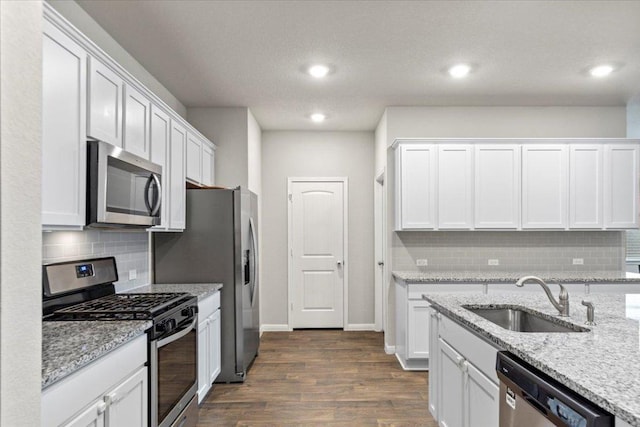 609 Bluffview Dr, Bastrop, TX 78602 - kitchen featuring stainless steel appliances, white cabinets, dark wood finished floors, tasteful backsplash, and recessed lighting