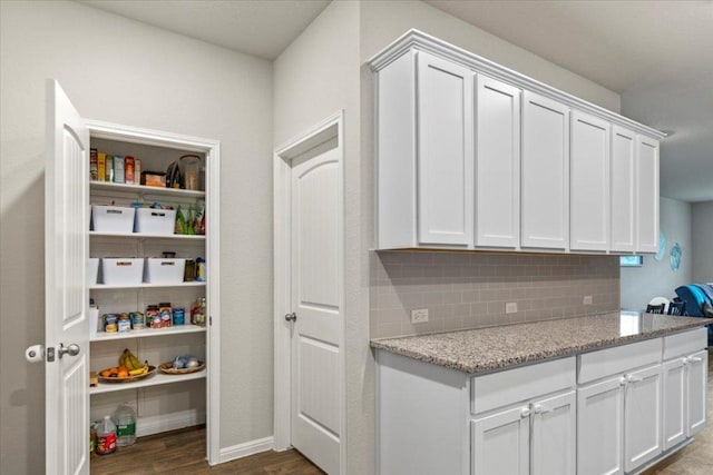 609 Bluffview Dr, Bastrop, TX 78602 - kitchen with backsplash, white cabinets, light stone countertops, and dark wood-style floors