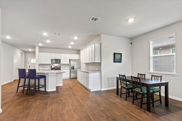 609 Bluffview Dr, Bastrop, TX 78602 - kitchen featuring stainless steel appliances, a kitchen island with sink, dark wood-style flooring, light stone counters, and recessed lighting