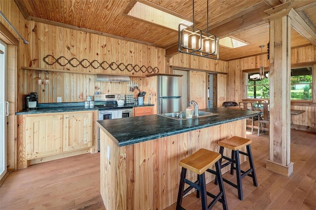 kitchen featuring wood walls, an inviting chandelier, a sink, wood ceiling, and appliances with stainless steel finishes