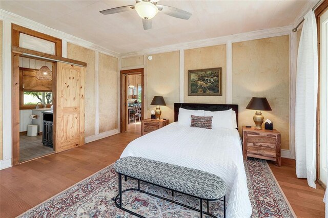bedroom with a ceiling fan, wood finished floors, connected bathroom, and ornamental molding