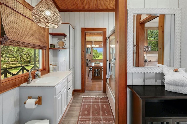 interior space with vanity, wood finished floors, a wealth of natural light, and a notable chandelier