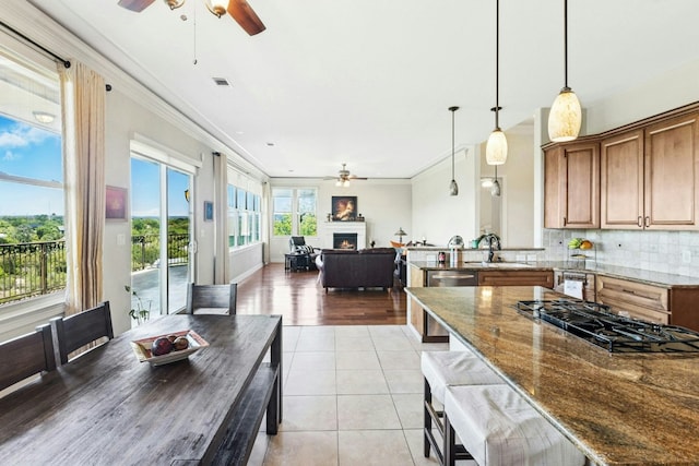 1204 Ogden Dr, Austin, TX 78733 - kitchen featuring a ceiling fan, black gas stovetop, ornamental molding, brown cabinets, and stainless steel dishwasher