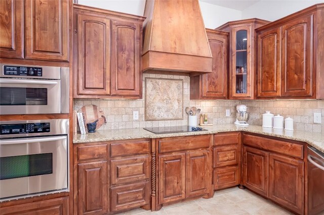 15 Chandon Ln, Lakeway, TX 78734 - kitchen featuring premium range hood, appliances with stainless steel finishes, light stone countertops, glass insert cabinets, and decorative backsplash