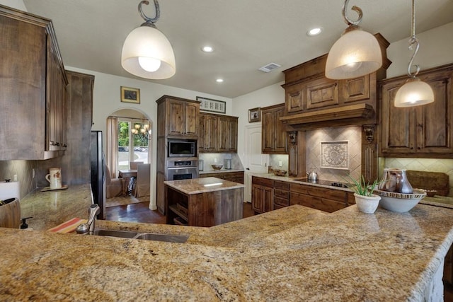 kitchen with light stone counters, a sink, arched walkways, stainless steel appliances, and visible vents