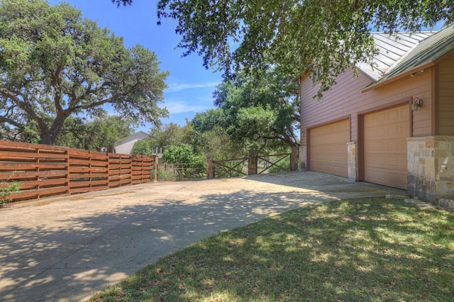 view of yard featuring a garage, driveway, and fence