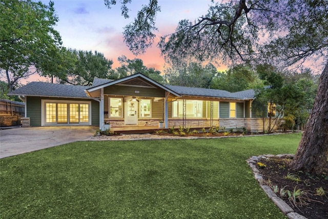 single story home featuring a lawn, concrete driveway, covered porch, and fence