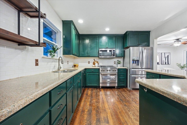 kitchen with decorative backsplash, stainless steel appliances, a sink, and green cabinetry