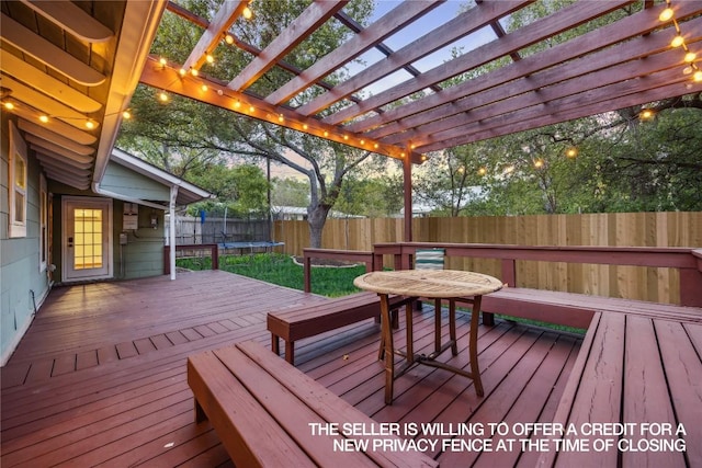 deck featuring a fenced backyard, a pergola, and a trampoline