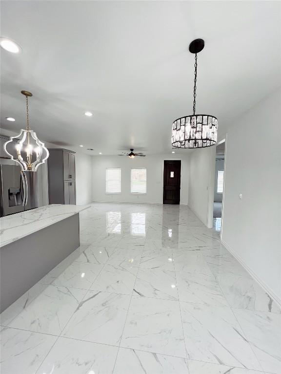 interior space with ceiling fan with notable chandelier, marble finish floor, and recessed lighting