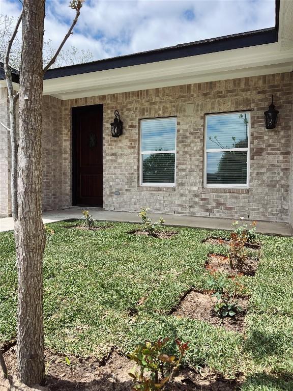 property entrance with a lawn and brick siding