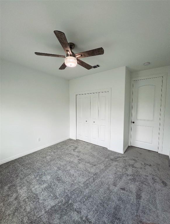 unfurnished bedroom with visible vents, carpet floors, a closet, baseboards, and ceiling fan