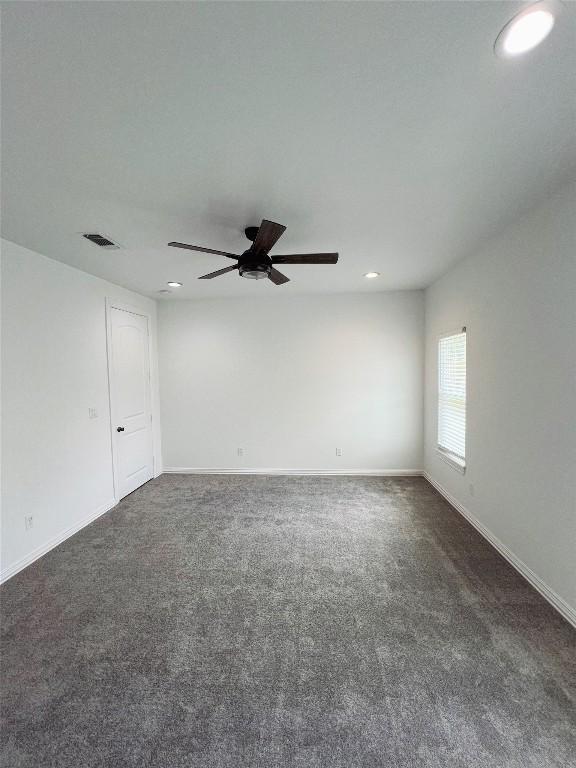 unfurnished room with dark carpet, a ceiling fan, visible vents, and recessed lighting