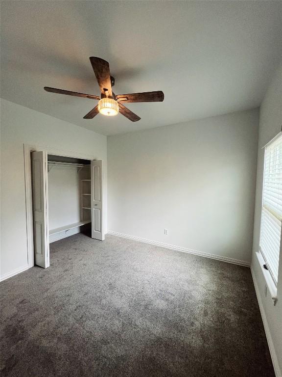 unfurnished bedroom featuring a ceiling fan, baseboards, carpet, and a closet
