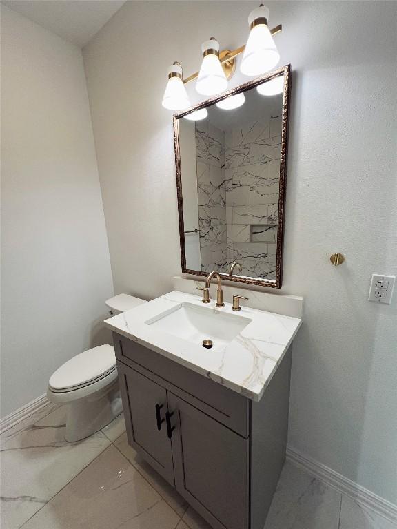 614 S Middle St, Flatonia, TX 78941 - bathroom with marble finish flooring, vanity, toilet, and baseboards