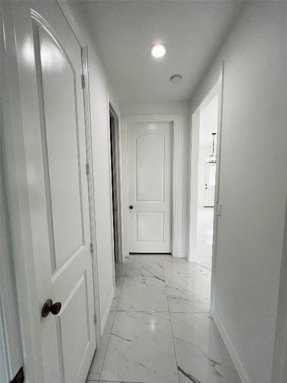 hallway featuring marble finish floor, baseboards, and recessed lighting