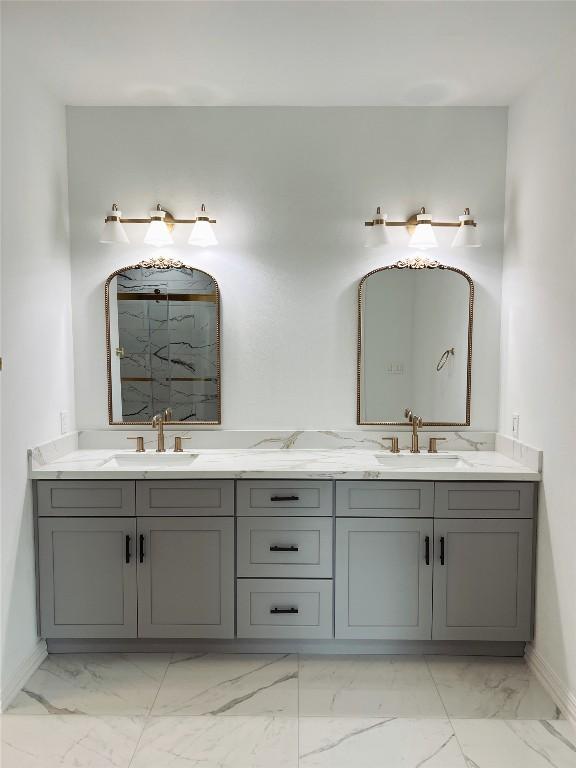 bathroom featuring baseboards, marble finish floor, a sink, and double vanity