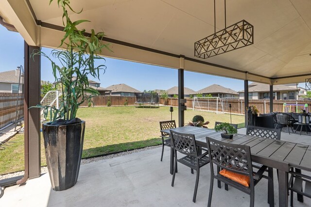 245 Six Shooter Dr, Kyle, TX 78640 - fenced backyard featuring a trampoline, outdoor dining area, a patio, and a residential view