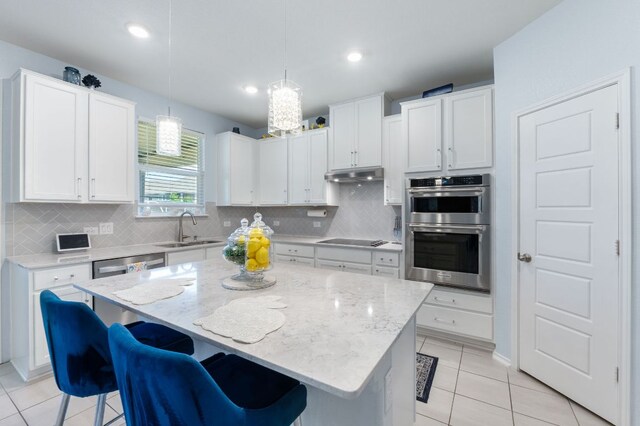 245 Six Shooter Dr, Kyle, TX 78640 - kitchen featuring appliances with stainless steel finishes, a kitchen bar, tasteful backsplash, light tile patterned floors, and white cabinets