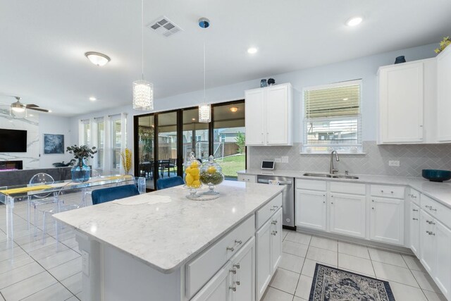 245 Six Shooter Dr, Kyle, TX 78640 - kitchen featuring dishwasher, open floor plan, light tile patterned flooring, decorative backsplash, and a center island