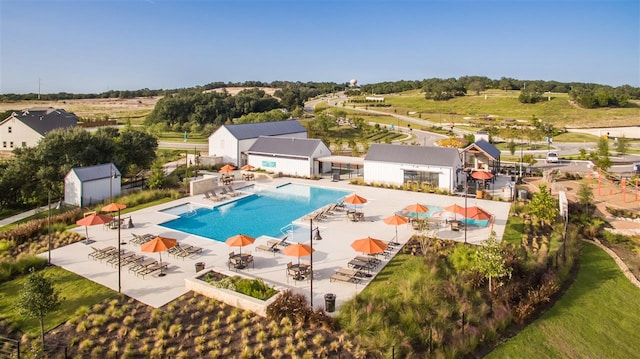 pool with an outdoor structure, a patio, and a storage shed