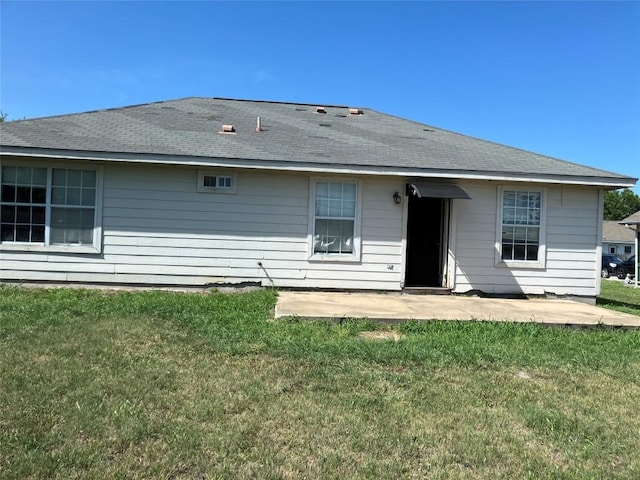 back of house with a lawn, a shingled roof, and a patio