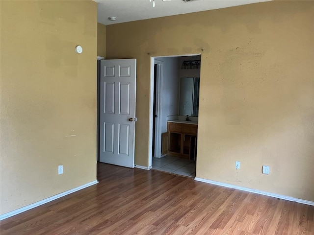 spare room with baseboards, wood finished floors, and a sink